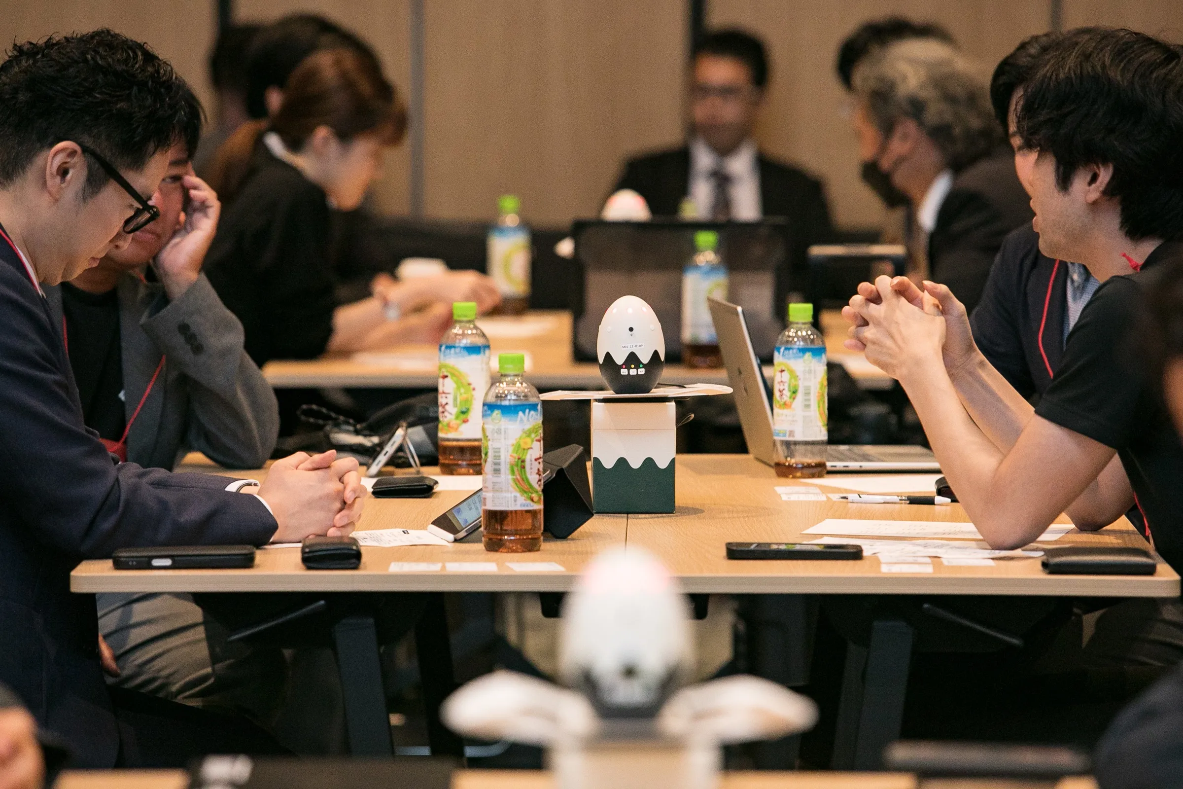 テーブル中央の装置を囲んで参加者が議論している様子